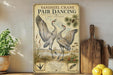 a vintage-style poster of two sandhill cranes in a field, with a wooden paddle and a potted plant in the foreground.
