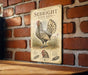 a vintage-style metal sign with an illustration of a chicken, mounted on a brick wall.