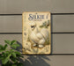 a sign with a picture of a white chicken, along with text and illustrations, mounted on a wall.