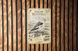 a poster with a bird illustration and text, mounted on a wooden wall.