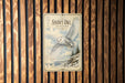 A vintage-style poster of a snowy owl in flight is displayed on a wooden wall.