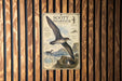 a poster of a seagull, which is a type of bird, hanging on a wooden wall.