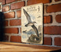 a vintage-style metal sign with illustrations and text, mounted on a brick wall.