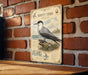 a vintage-style metal sign with a detailed illustration of a sea bird, specifically a sea tern, mounted on a brick wall.