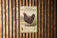 a sign for Speckled Sussex Chicken, which is a breed of chicken known for its speckled feathers. The sign is mounted on a wooden wall with vertical slats.