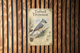 a vintage-style metal sign with a bird illustration, mounted on a wooden wall.