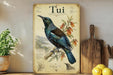 a vintage-style poster of a blue and green bird, likely a toucan, perched on a branch with flowers. The poster is displayed on a shelf next to a wooden cutting board and a potted plant.