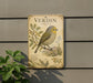 a vintage-style metal plaque with a detailed illustration of a bird perched on a branch, surrounded by plants and foliage.