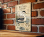 a vintage-style illustration of a Western Grebe, a type of water bird, on a brick wall.
