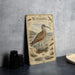 A metal sign with an illustration of a bird, likely a Whimbrel, standing on a beach.
