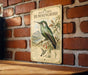 A vintage-style metal sign featuring an illustration of a hummingbird is mounted on a brick wall.