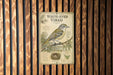 a vintage-style sign with a bird illustration, mounted on a wooden wall.