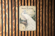 A vintage-style poster of a white peacock is displayed on a wooden wall.
