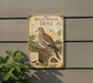 a vintage-style metal sign with illustrations and text, mounted on a wall next to a plant.