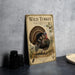 A wooden sign with a turkey illustration and text, placed on a gray countertop next to some black camera lenses.