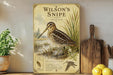 A vintage-style illustration of a Wilson's Snipe bird, with a label indicating it is a species of marsh bird and a description of its features.