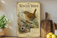 A vintage-style poster of a small brown bird, likely a wren, perched on a branch with a detailed illustration of the bird and its natural habitat. The poster is displayed on a wall, surrounded by various kitchen items such as a wooden cutting board, a potted plant, and a bowl of fruit.