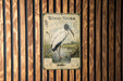 A vintage-style poster of a wood stork, featuring illustrations and text, is displayed on a wooden wall.