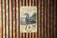 A vintage-style poster of a yellow-billed looon, a type of water bird, is displayed on a wooden wall.