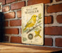 A vintage-style metal sign with illustrations and text about a yellow warbler, mounted on a brick wall.