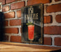 A framed illustration of a cocktail called "151 Swzzle" is displayed on a brick wall.