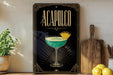 a decorative sign with the word "ACAPULCO" on it, along with an illustration of a cocktail glass and a lemon. The sign is placed on a wooden surface, and there are some potted plants and kitchen utensils visible in the background.