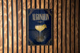 A poster for "Algonquin" cocktail, featuring a glass of the drink with a lemon twist, displayed on a wooden wall.