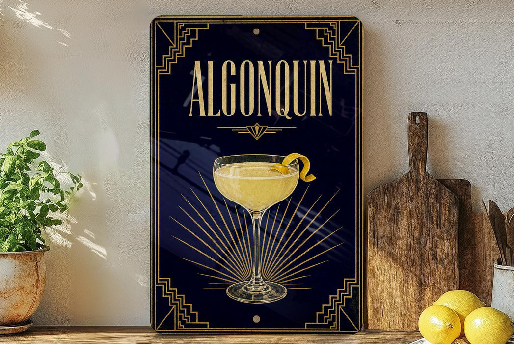 A framed poster of a cocktail called Algonquin, featuring a glass of the drink with a lemon twist, is displayed on a wall next to a wooden cutting board and a potted plant.