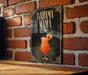 A framed poster of a tropical drink, likely a Bahama Mama cocktail, is displayed on a brick wall.