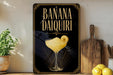 A decorative sign for a banana daiquiri cocktail, featuring an illustration of a glass filled with the drink and a lemon slice.
