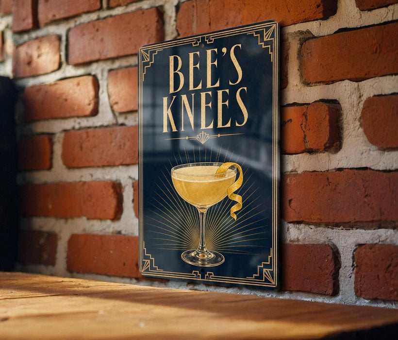 A poster with the text "BEE'S KNEE'S" and an illustration of a cocktail glass with a lemon twist.