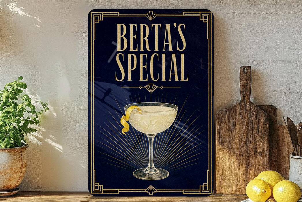 A framed poster with the text "BERTA'S SPECIAL" and an illustration of a cocktail glass with a lemon twist, placed on a wooden shelf next to a cutting board and a potted plant.