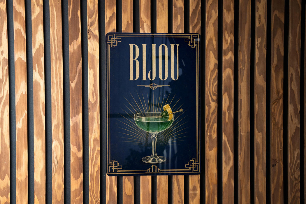 A poster with the word "BJOU" displayed prominently, featuring a glass of green liquid and a lemon slice.