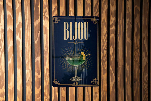 A poster with the word "BJOU" displayed prominently, featuring a glass of green liquid and a lemon slice.
