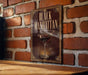A sign with the text "BLACK MANHAITAN" and an illustration of a martini glass is displayed on a brick wall.