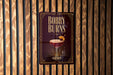 A sign for "Bobby Burns" cocktail is displayed on a wooden wall.