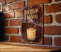 A sign for "Bourbon Eggnog" is displayed on a brick wall, featuring an illustration of a glass of eggnog with a cinnamon stick.