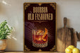 A framed advertisement for bourbon old fashioned, featuring an illustration of a glass of bourbon with an orange peel on the rim.