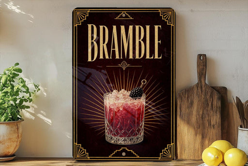 a decorative sign for a drink called "Bramble" with a glass of the drink and garnish, placed on a wooden surface next to a cutting board and some lemons.
