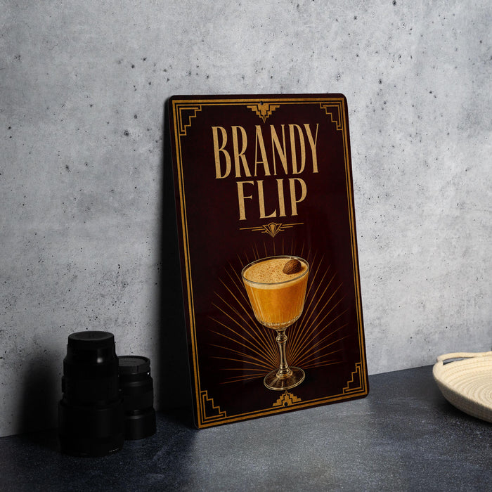 A dark brown sign with gold lettering and an illustration of a cocktail on a table.