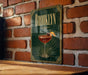 A green sign with gold trim displays the word "Brooklyn" and an illustration of a cocktail glass with a cherry on a brick wall.