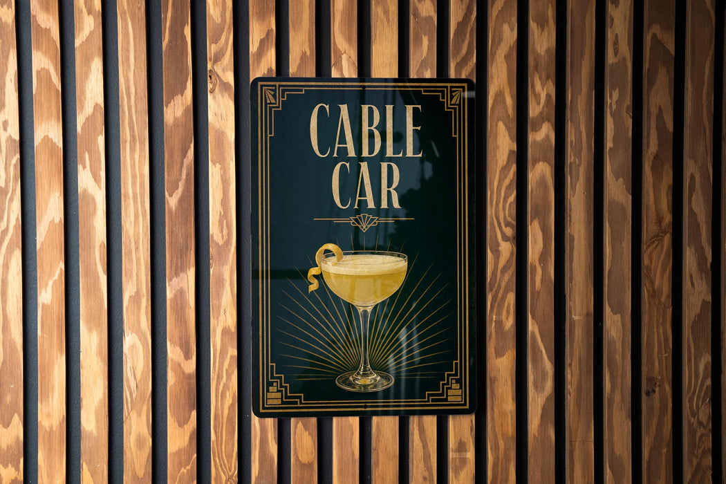 a sign for a bar called "CABLE CAR", which is displayed on a wooden wall.