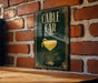 a sign for a bar called "Cable Car" with a glass of yellow liquid and a lemon twist on the sign.