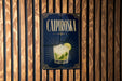 A sign for a Caipiroski cocktail is displayed on a wooden wall.