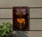 a sign for a cocktail called "Calvados Sider" with a glass illustration, placed on a wall next to a plant.