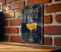 A sign with the text "CHAMPAGNE COCKTAIL" and an illustration of a champagne glass with a lemon twist.