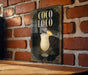 A poster or sign for a cocktail called "Coco Loco" is displayed on a brick wall.