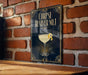 a sign with a cocktail glass and a lemon twist, mounted on a brick wall.