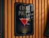 A sign for a cocktail called "Cosmo Politan" is displayed on a wooden wall.