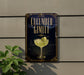 a decorative sign with a cucumber rim cocktail illustration, hanging on a wall next to a plant.